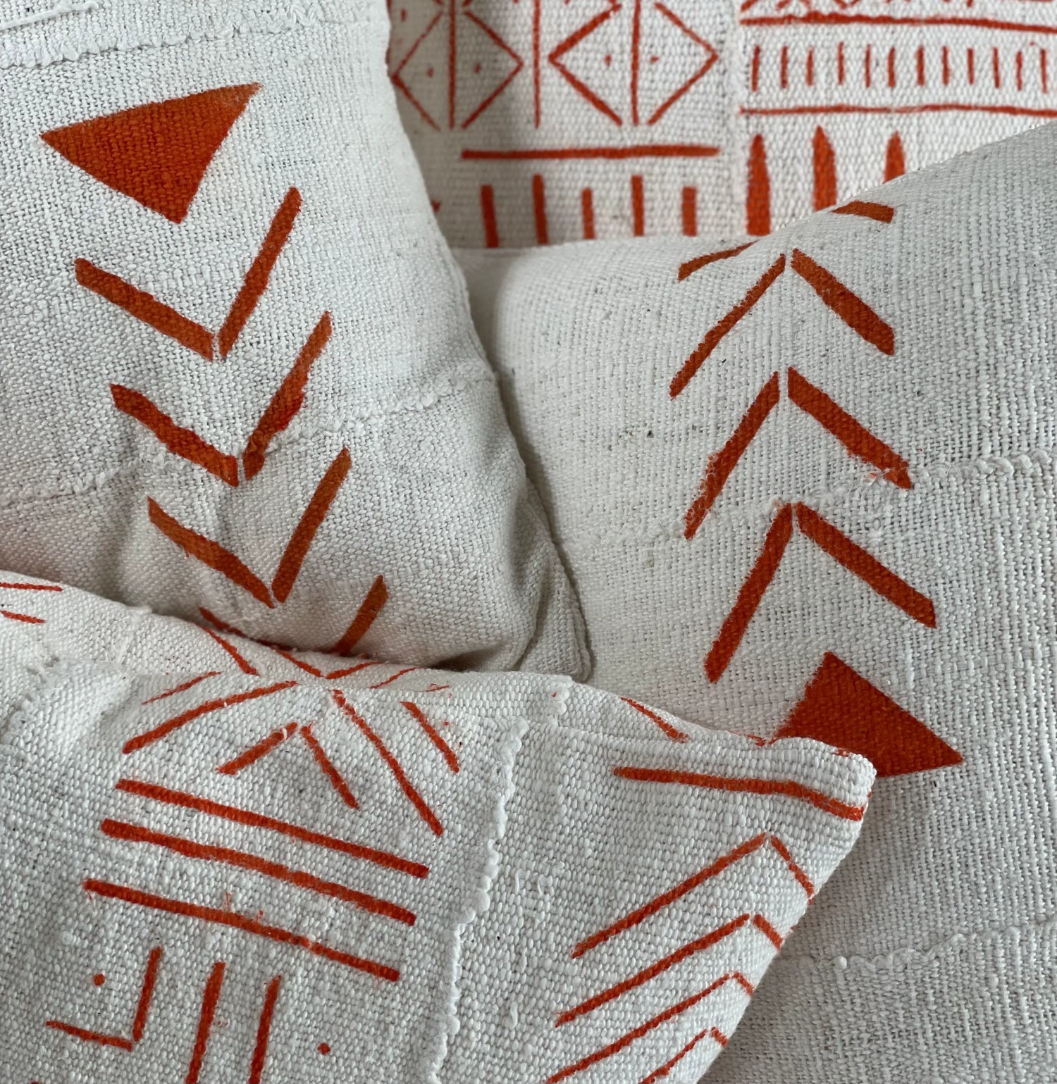 Détails de la housse de coussin éthnique UCHAWI, UPENDO, NYINGI en bogolan blanc à motifs géométriques oranges par Studio Matongé