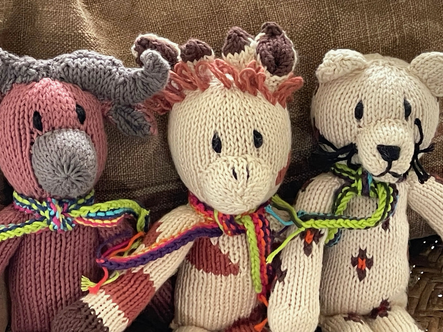 ANGELO, doudou buffle chataigne. Adorable avec sa petite écharpe multicolore. Fait main au Kenya par les tricoteuses de la coopérative Kenana Knitters. En coton bio certifié GOTS, teintures non toxiques. Ici avec la girafe LEONTINE et le léopard ERNEST. Utilisables dès la naissance.