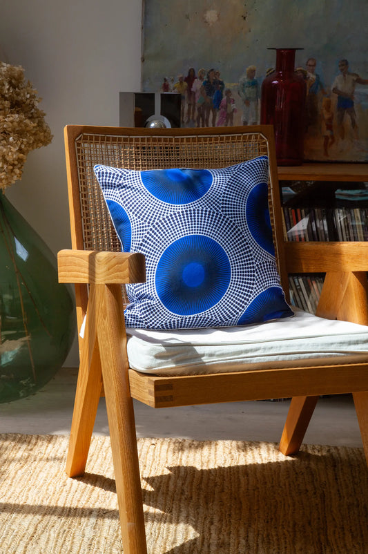 Au salon, housse de coussin éthnique WAALI en wax imprimé de grands cercles bleu, blanc et noir  - Studio Matongé. Notre housse de coussin WAALI est présentée ici en format carré et dimension 40 x40 cm. Disponible en d'autres formats et tailles. 