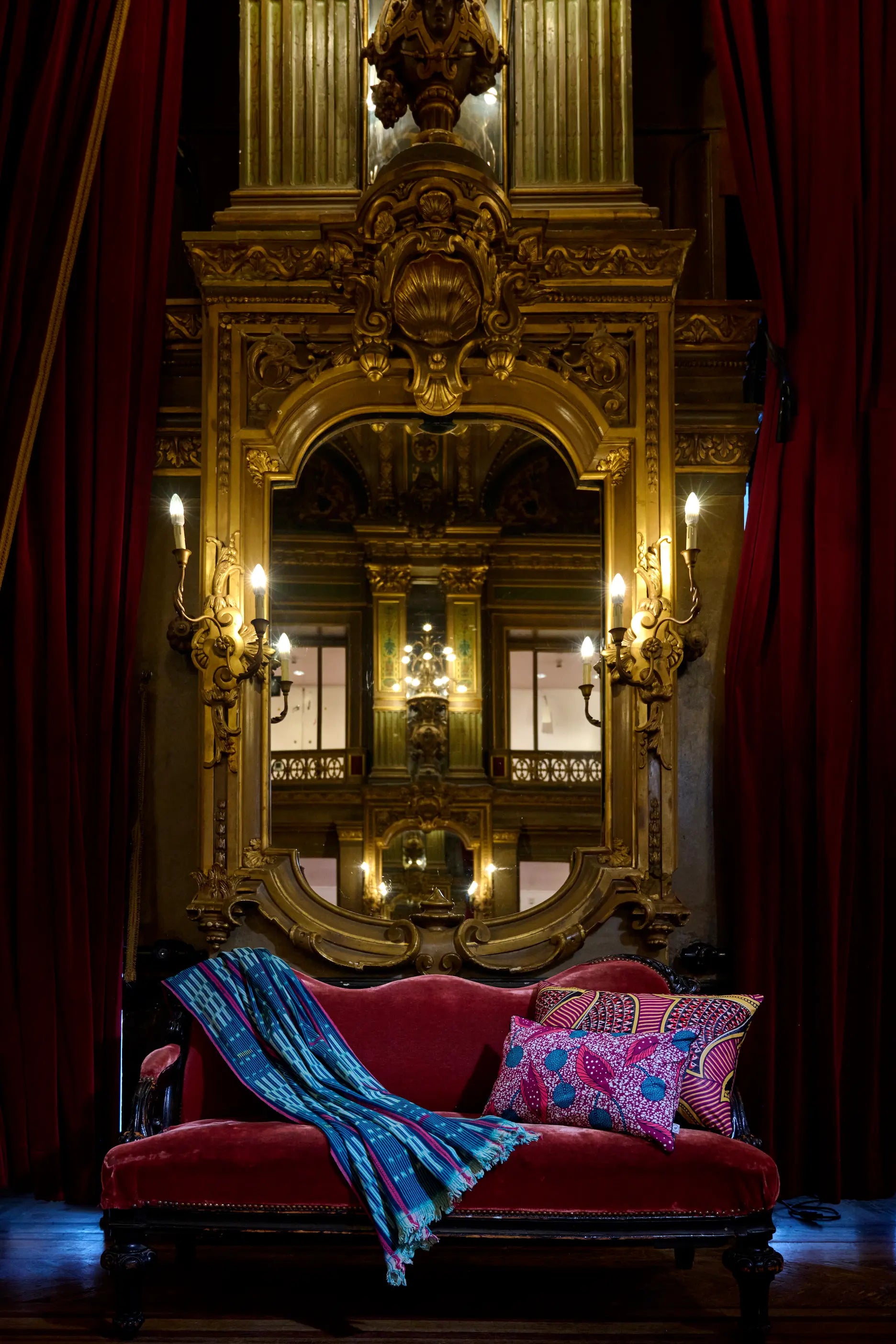 Dans les magnifiques décors du grand foyer de l'Opéra de la Monnaie de Bruxelles, housse de coussin en wax - WIMBI et LINDEN - Studio Matongé. Fait main en Belgique. Ici avec un plaid baoulé vintage tissé main en Côte d'Ivoire.