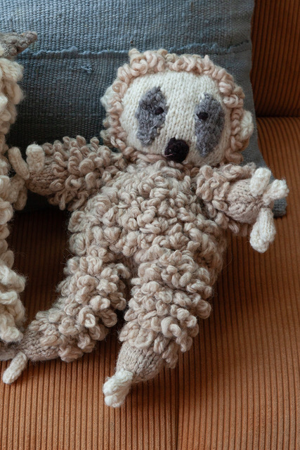 MAURICE, doudou paresseux en laine bio, fait main par les femmes artisans de la coopérative Kenana Knitters au Kenya. Ici avec la housse de coussin en bogolan de coton gris MSINGI.