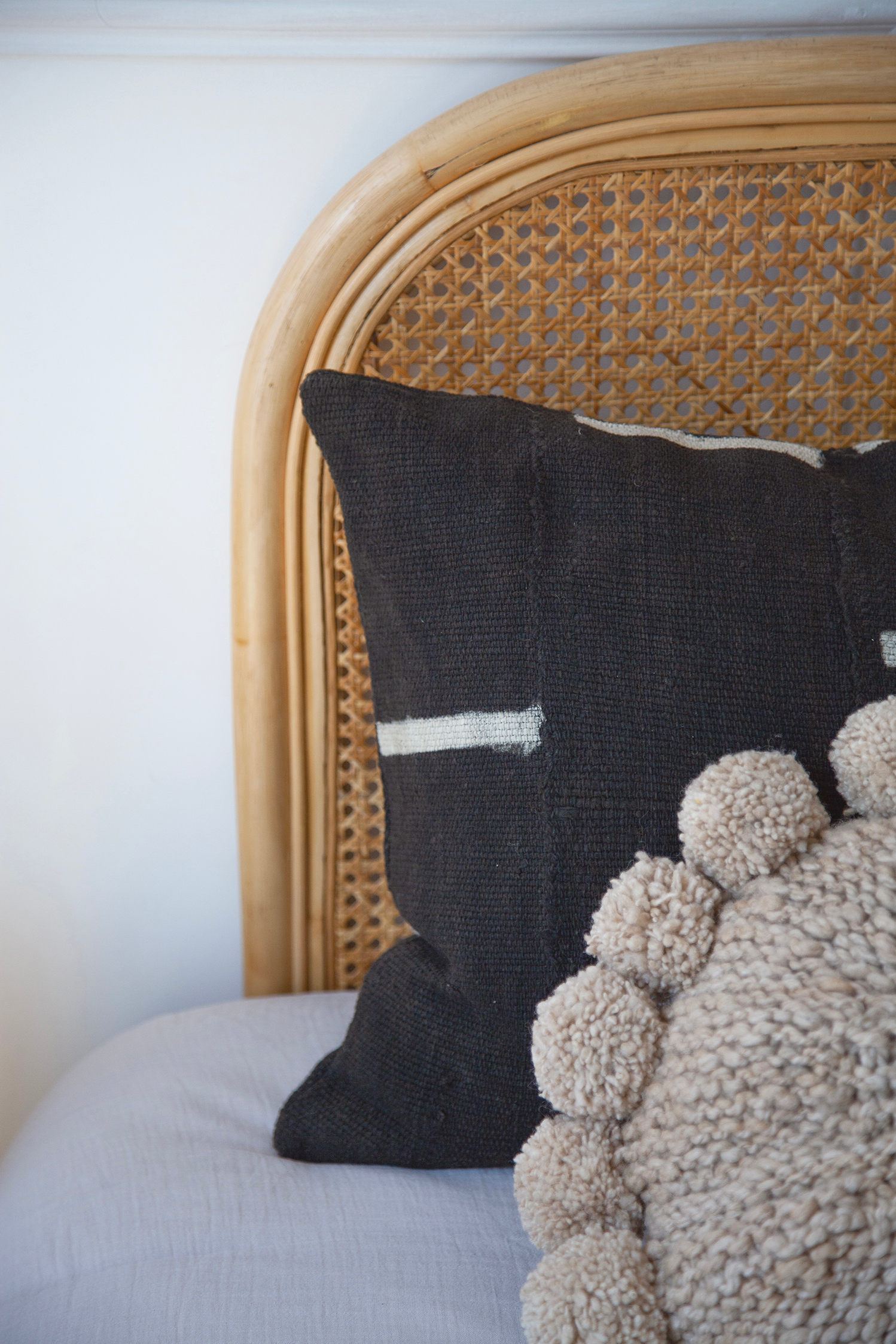 Coussin rond à pompons en laine beige BONBONSI et housse de coussin GIZA en bogolan noir par Studio Matongé. Faits main. 