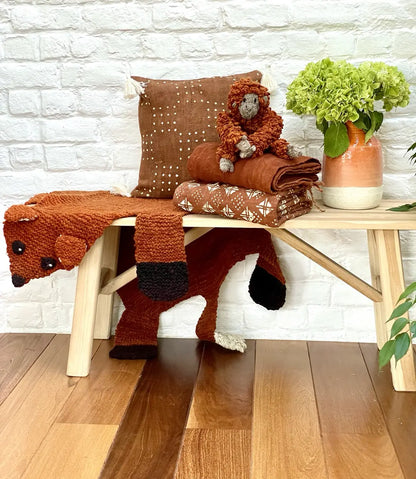 Tapis renard en laine bio éco-responsable - FOXY - Studio Matongé
Housse de coussin en bogolan terracotta KUTU. 
Plaid en bogolan LENGO terracotta. 
Doudou singe tamarin en laine fait main TAMY. 