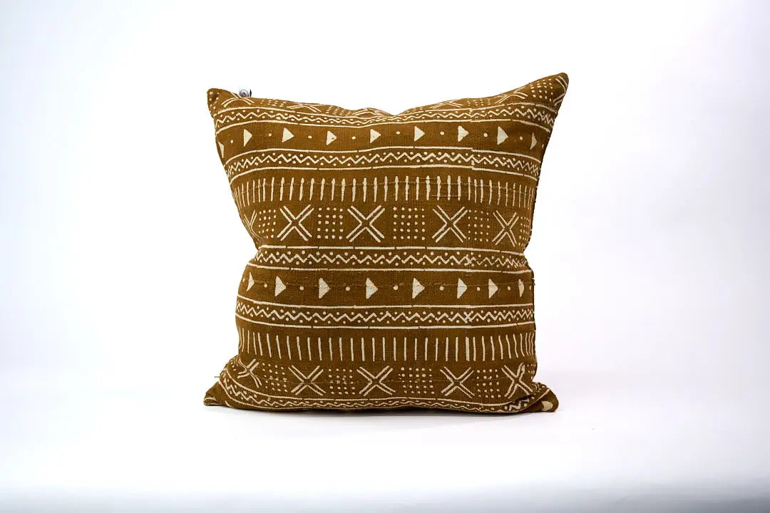 Housse de coussin ethnique KEUR 60 x 60cm par Studio Matonge. Confectionné en Belgique à partir de tissu africain bogolan ocre à motifs blancs, tissés et teints à la main par des artisans de la région de Ségou.