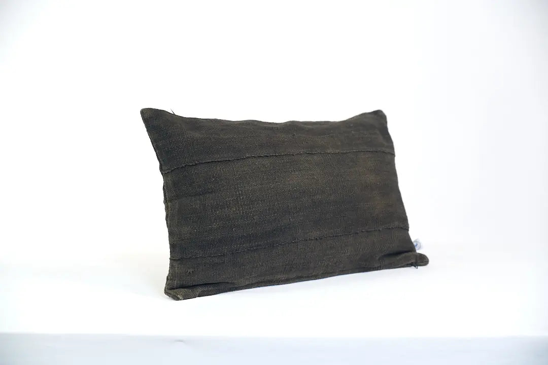 Housse de coussin noire en bogolan de coton bio par Studio Matongé. Pièces uniques tissées, filées et confectionnées à la main. Format rectangle 30 x 50 cm. 