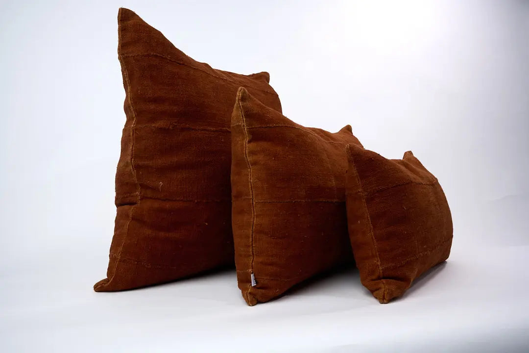 Housses de coussin terracotta en bogolan de coton bio par Studio Matongé. Pièces uniques tissées, filées et confectionnées à la main. Formats rectangle 30 x 50 cm & 40 x 60 cm. Format carré 50 x 50 cm.