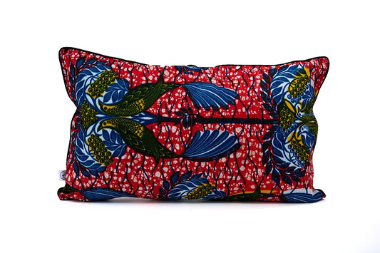 Housse de coussin NDEGE par Studio Matongé. En wax rouge orné d'oiseaux jaunes et bleus. 30 x 50 cm. 100% coton. Finition passepoil noir. Housse zippée.  